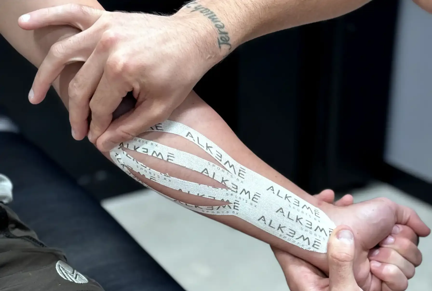 Kinesio tape being applied to a knee at the end of a treatment session at Alkemē Sports Rx in Davie, FL
