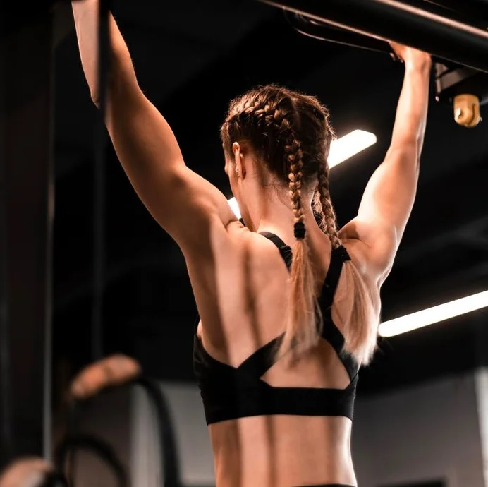 Athlete performing pull-up exercise, showcasing strong back muscles and commitment to physical training at Alkeme Sports RX.